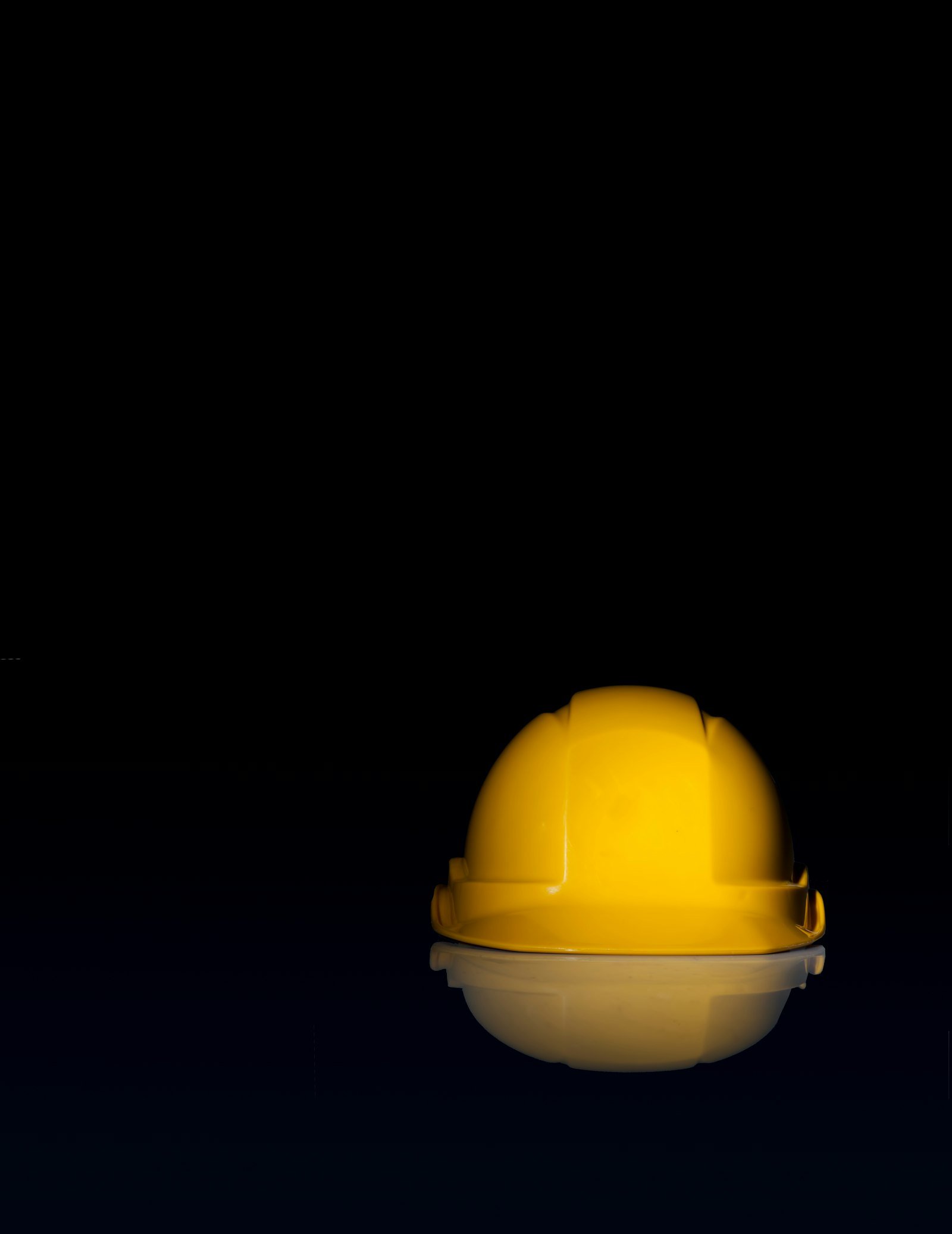 Casque de chantier jaune posé sur un fond noir