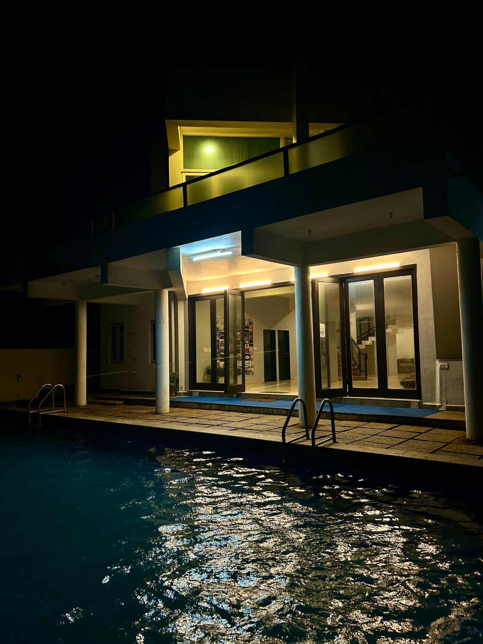 Piscine éclairée de nuit devant une maison