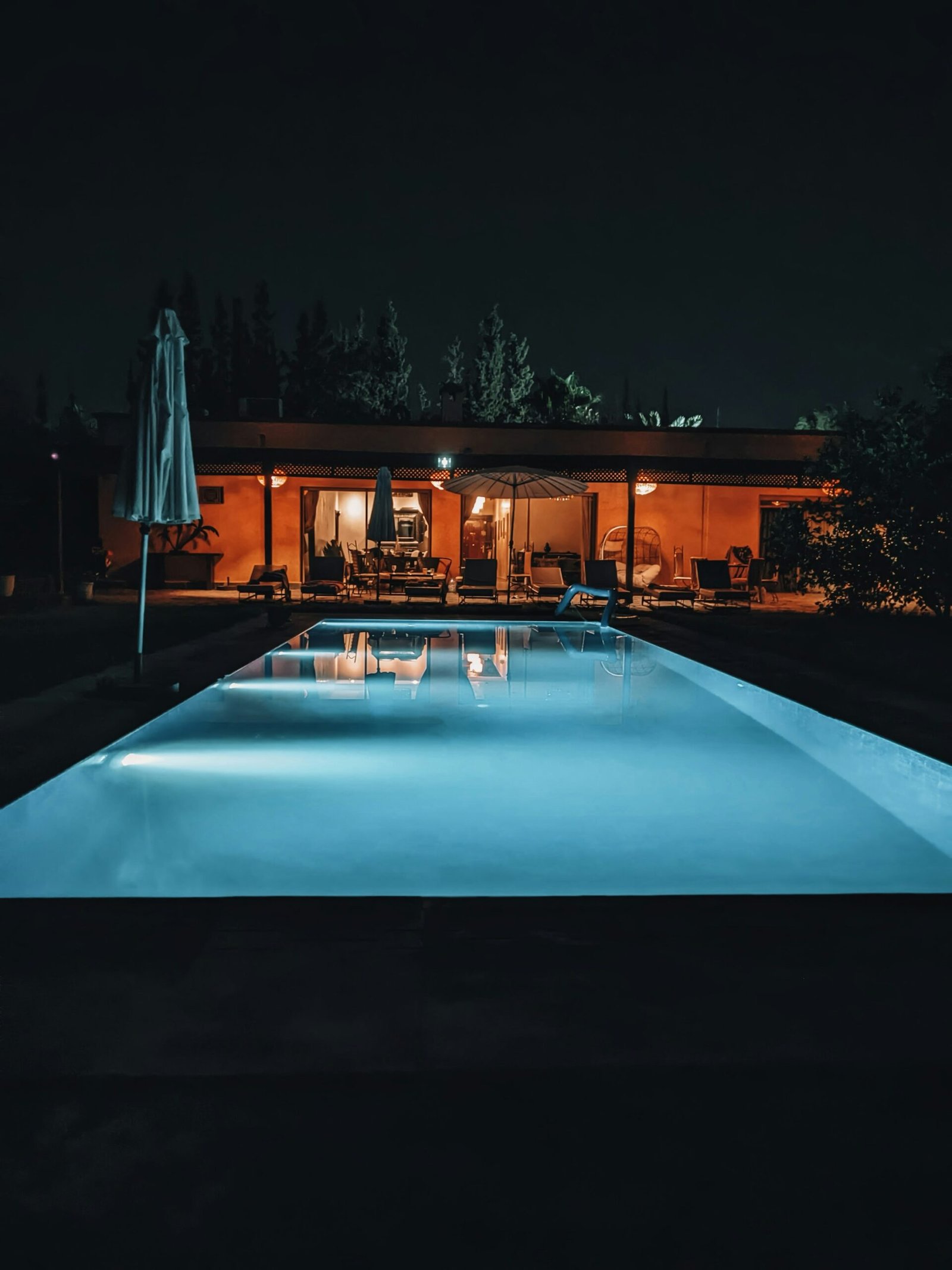 Piscine éclairée de nuit devant une maison