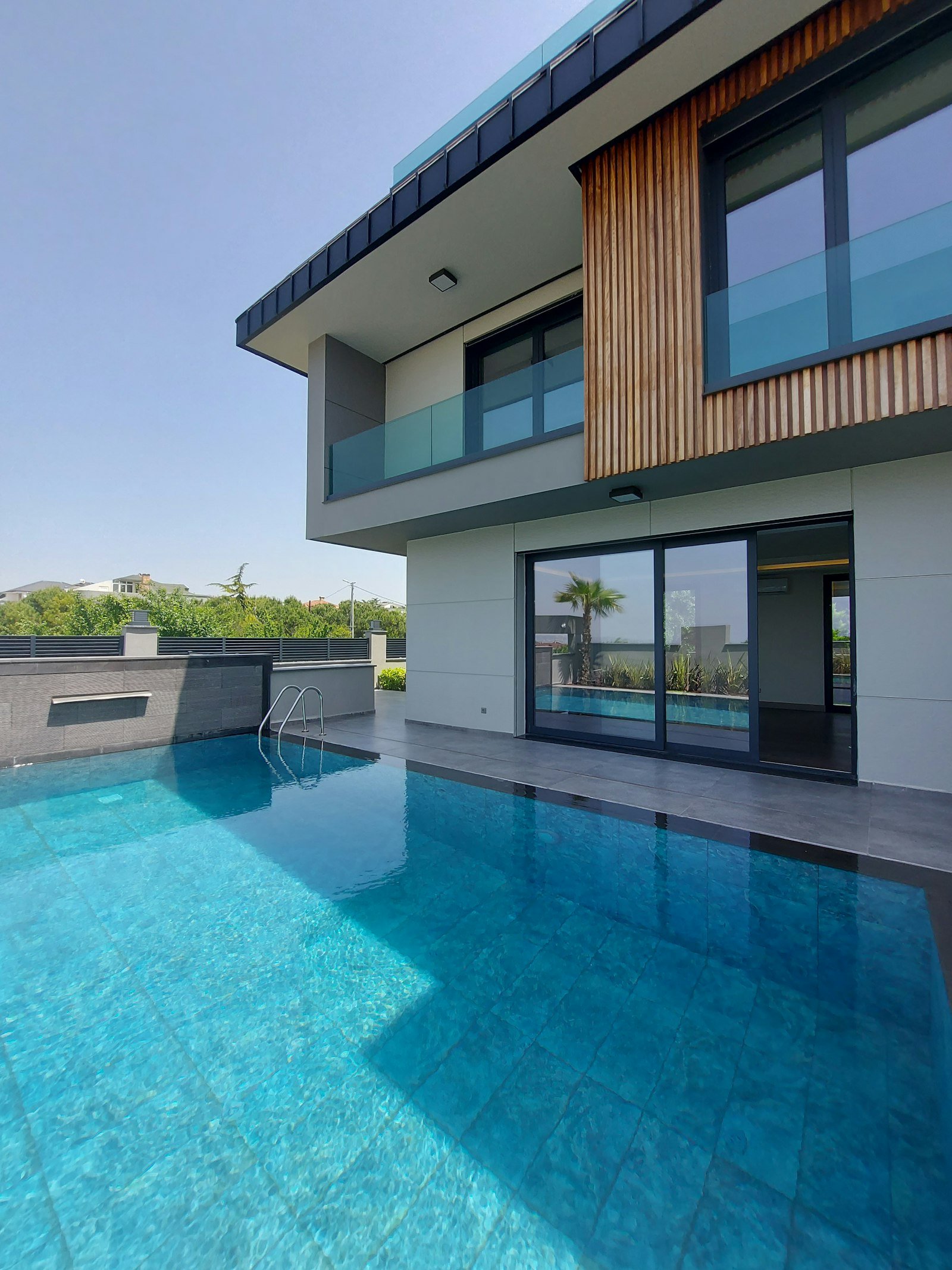Maison moderne avec balcons vitrés au bord d’une piscine